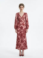 woman wearing a pink and red floral print satin maxi wrap dress with long bishop sleeves and a v-neck, standing against a white background