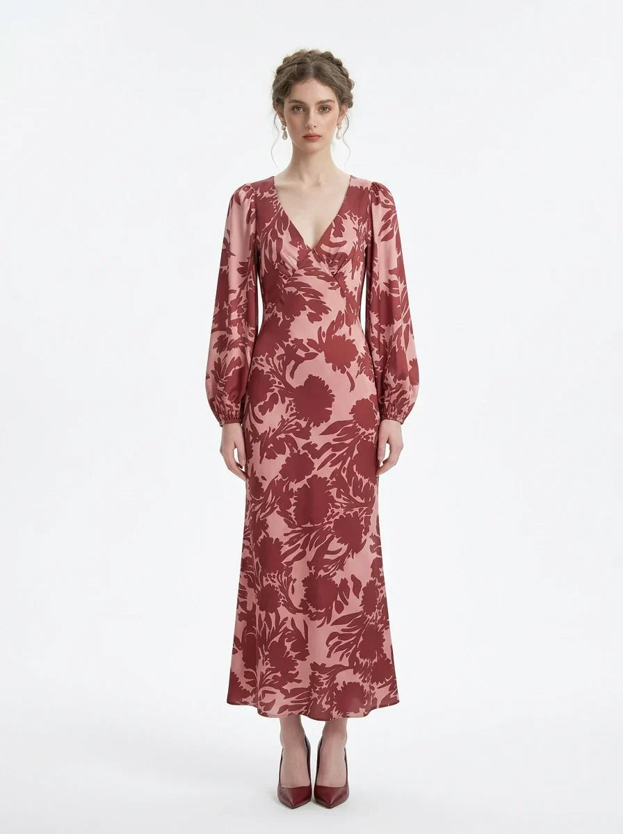 woman wearing a pink and red floral print satin maxi wrap dress with long bishop sleeves and a v-neck, standing against a white background