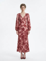woman wearing a pink and red floral print satin maxi wrap dress with long bishop sleeves and a v-neck, standing against a white background
