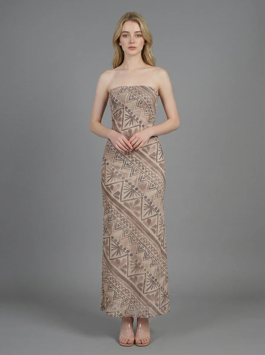 Woman wearing a strapless, patterned maxi dress standing against a grey background, front view.