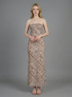 Woman wearing a strapless, patterned maxi dress standing against a grey background, front view.