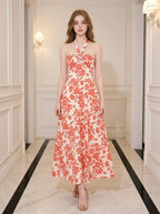 Woman wearing a cream and coral floral print halter midi dress, standing in a hallway.