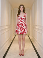 Woman standing in a hallway wearing a red and white floral print dress and red strappy heels
