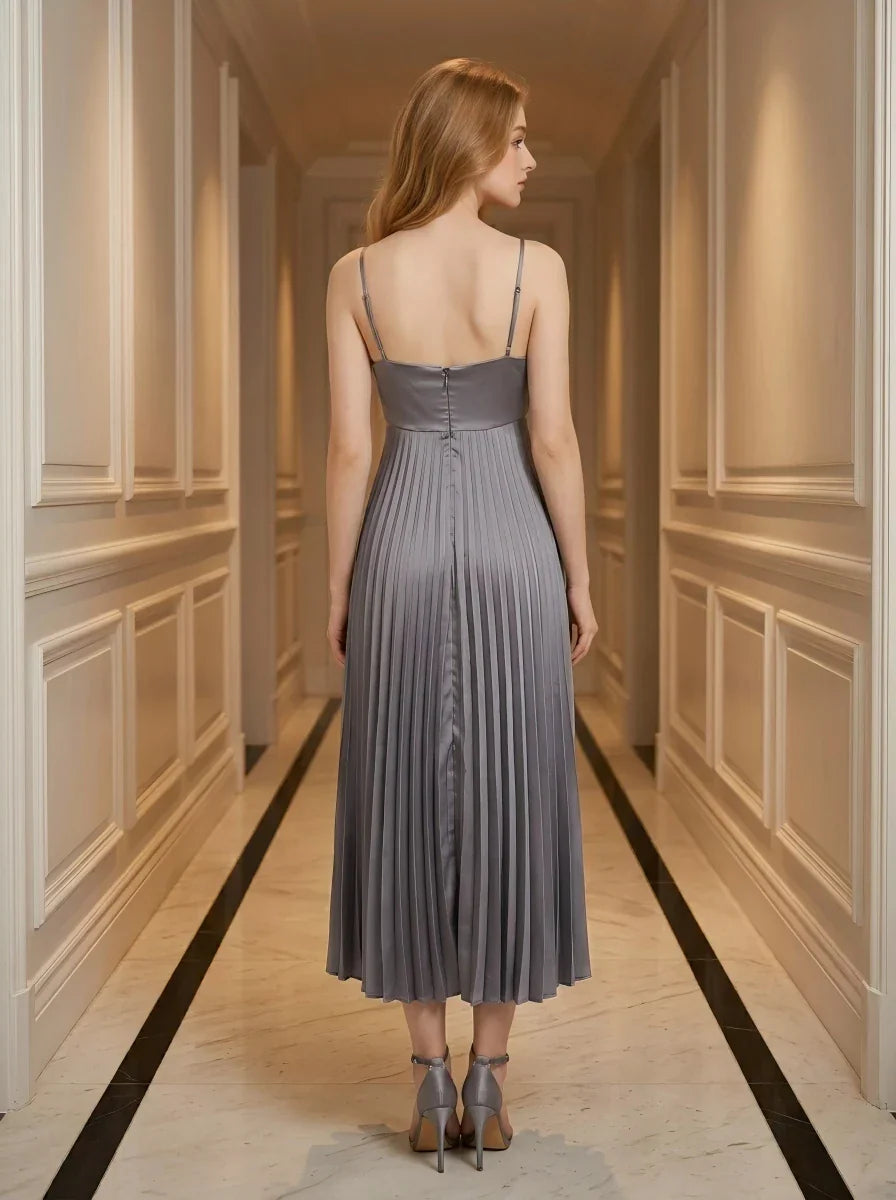 Back view of a woman wearing a grey satin midi dress with spaghetti straps and a square neckline, standing in a hallway.