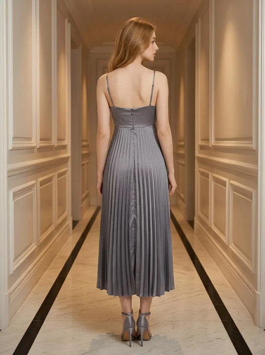 Back view of a woman wearing a grey satin midi dress with spaghetti straps and a square neckline, standing in a hallway.