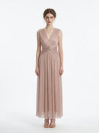 Woman in a rose gold shimmering metallic A-line V-neck sleeveless floor-length formal gown, front view