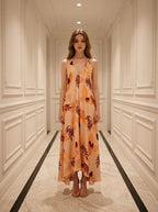 Woman standing in a hallway wearing a long, floral print, halter neck dress with an open back.
