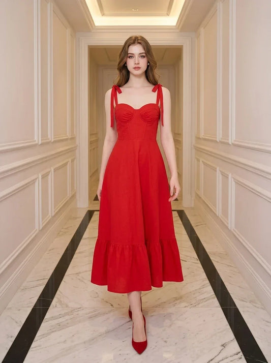 Woman wearing a red midi dress with tie straps and ruffle hem, standing in a hallway.
