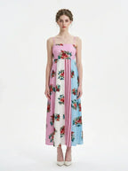 woman in a pink, blue, and white floral print maxi dress with spaghetti straps, standing against a white background
