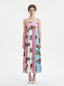 woman in a pink, blue, and white floral print maxi dress with spaghetti straps, standing against a white background