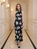 woman wearing a black floral maxi dress with a halter neck standing in a hallway