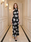 woman wearing a black floral maxi dress with a halter neck standing in a hallway