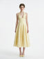 Woman wearing a yellow halter neck midi dress with a full skirt, standing against a white background.