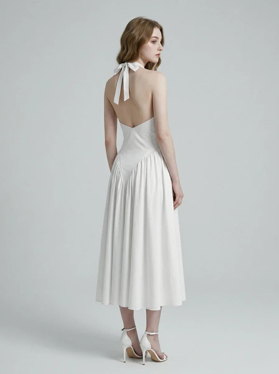 Back view of a woman in a white halter neck midi dress, showing the open back and tie closure.