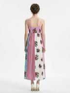 back view of a woman in a pink, blue, and white floral print maxi dress with spaghetti straps, standing against a white background