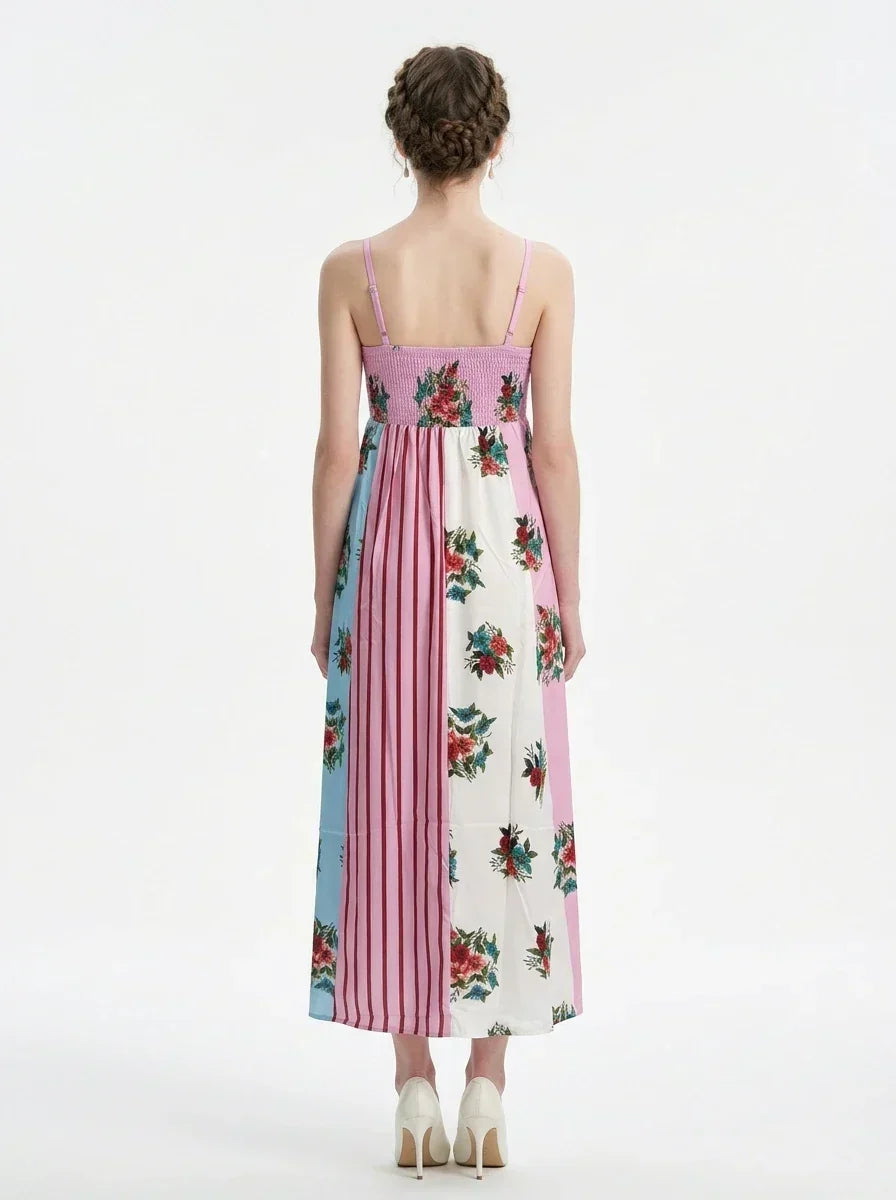 back view of a woman in a pink, blue, and white floral print maxi dress with spaghetti straps, standing against a white background