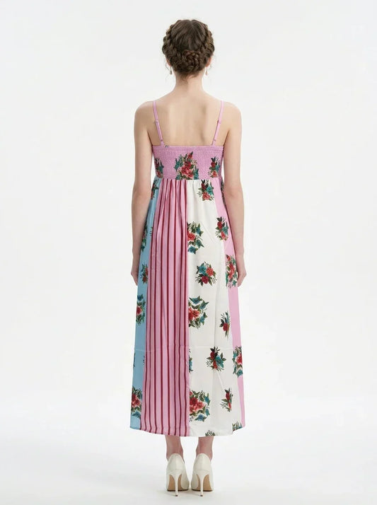 back view of a woman in a pink, blue, and white floral print maxi dress with spaghetti straps, standing against a white background