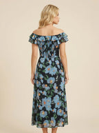 Back view of a woman in a black off-the-shoulder midi dress with a blue floral print and smocked bodice