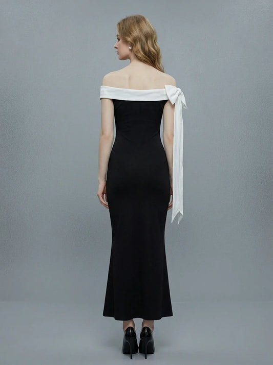 Rear view of a woman in a black off-the-shoulder mermaid gown with a white sash and bow detail.