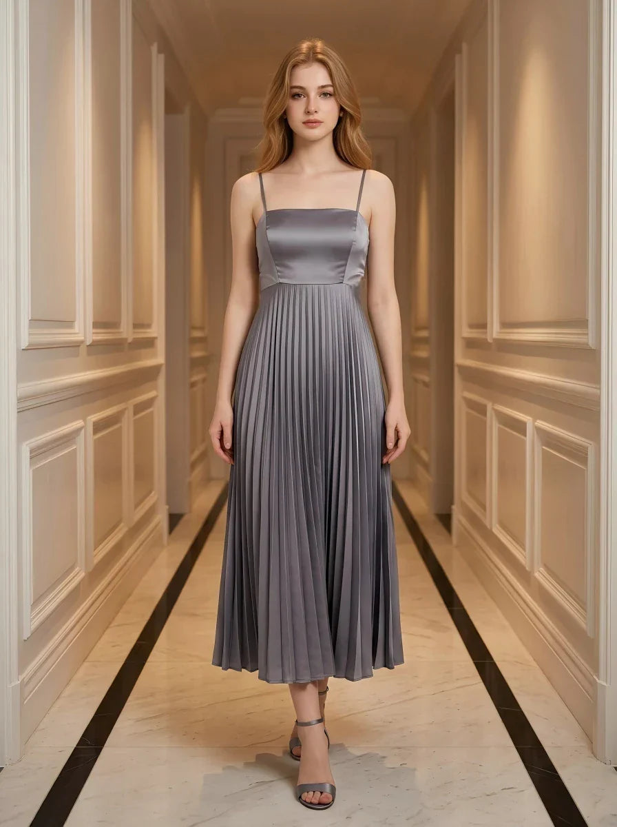 Woman wearing a grey satin midi dress with spaghetti straps and a square neckline, standing in a hallway.