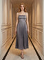 Woman wearing a grey satin midi dress with spaghetti straps and a square neckline, standing in a hallway.