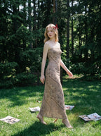 Woman wearing a strapless, patterned maxi dress walking on grass in a wooded area.