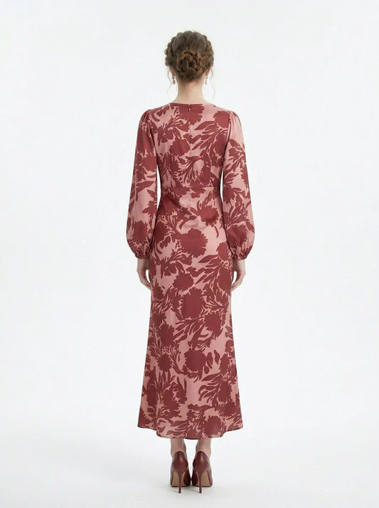 back view of a woman wearing a pink and red floral print satin maxi wrap dress with long bishop sleeves and a v-neck, standing against a white background