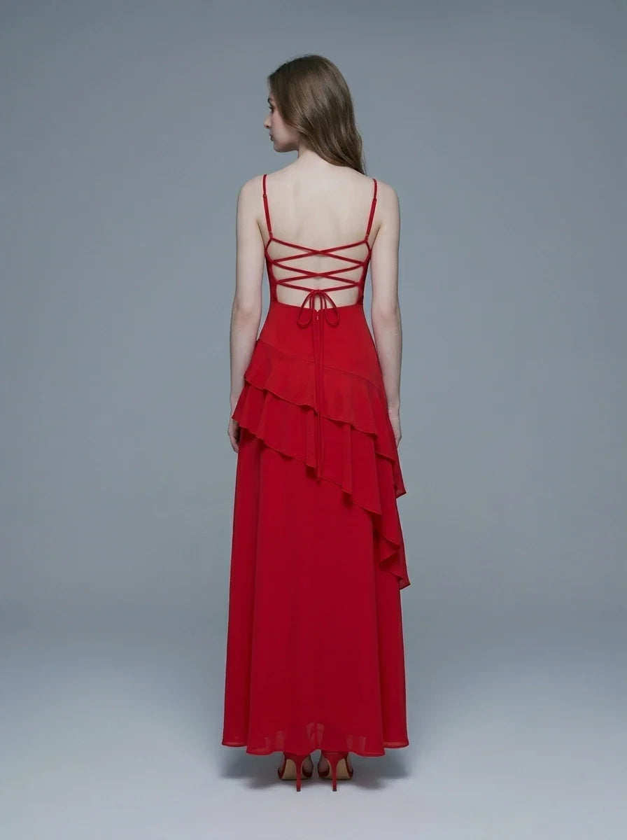 Woman wearing a red floor-length chiffon dress with tiered ruffles and spaghetti straps, back view showing lace-up detail.