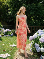 Woman walking through a garden with hydrangeas, wearing a strapless floral print midi dress.