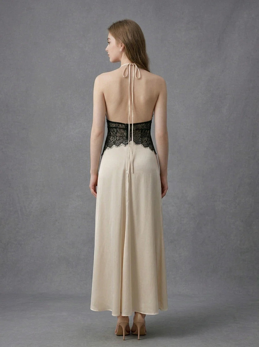 Back view of a woman in a cream satin maxi dress with black lace waist detail and a halter neckline.
