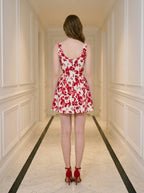 Back view of a woman in a red and white floral print dress and red strappy heels
