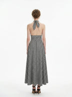 Woman wearing a black and white gingham halter maxi dress, back view