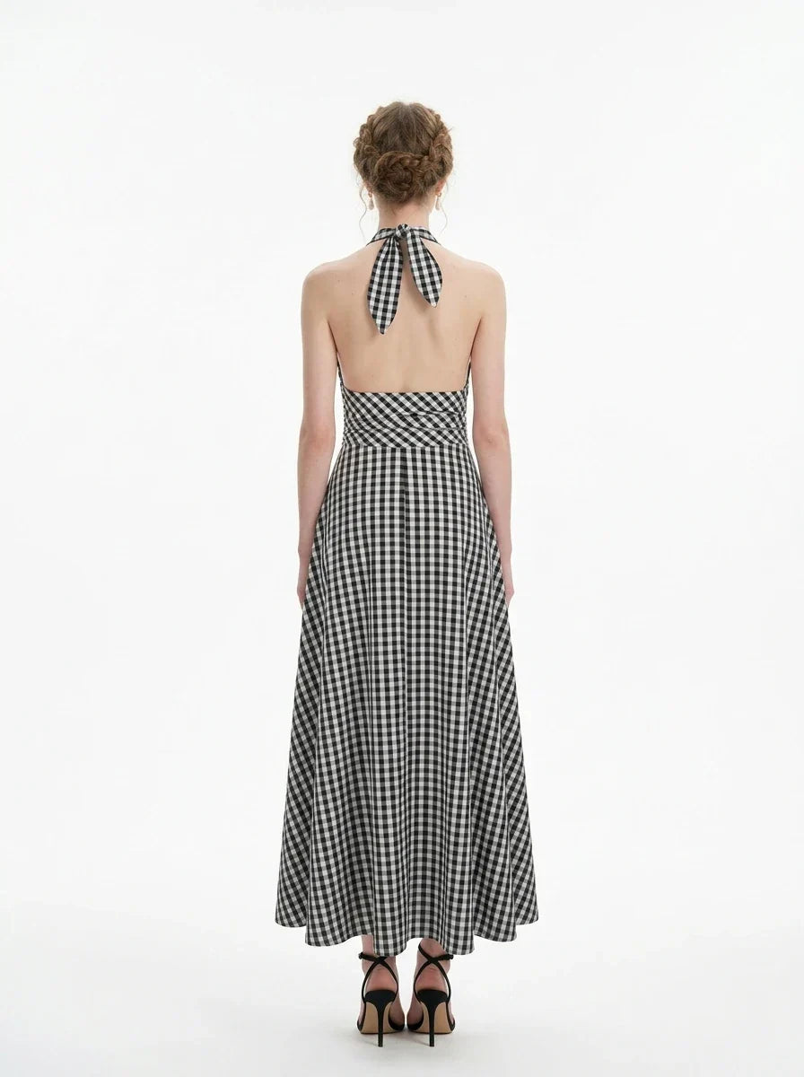Woman wearing a black and white gingham halter maxi dress, back view