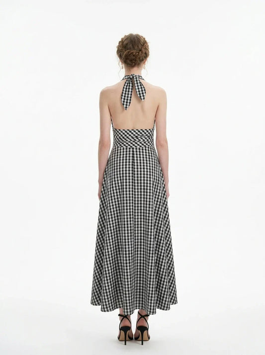 Woman wearing a black and white gingham halter maxi dress, back view