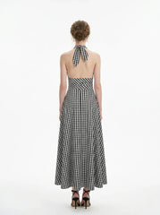 Woman wearing a black and white gingham halter maxi dress, back view