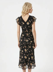 Back view of a woman in a black floral print midi dress with a tie waist.