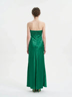 Woman standing in a green strapless satin gown with a pleated bodice, back view