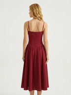 Woman wearing a deep red fit and flare midi dress with spaghetti straps, back view