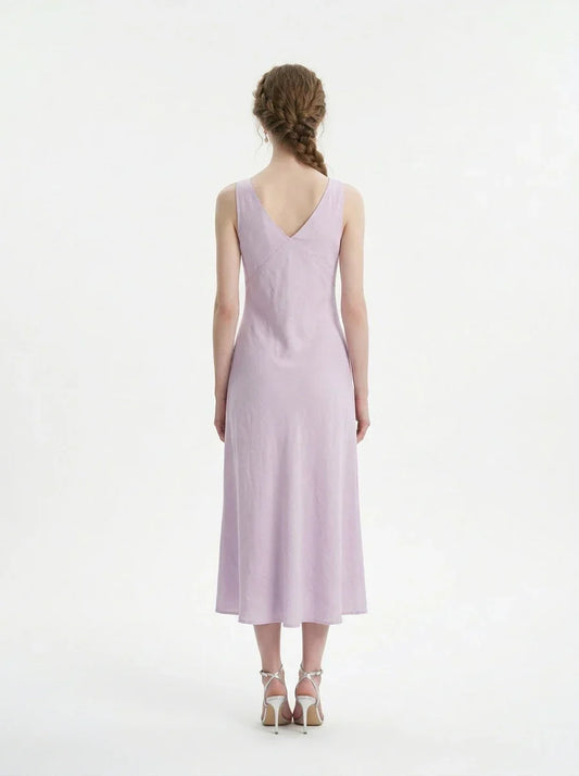 Back view of a model wearing a lavender midi dress with a V-neckline and sleeveless design, standing against a white background.