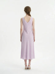 Back view of a model wearing a lavender midi dress with a V-neckline and sleeveless design, standing against a white background.