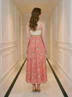 Back view of a woman in a coral A-line midi dress with spaghetti straps and a square neckline, standing in a hallway.