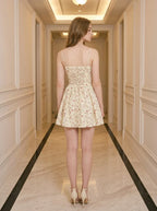Back view of a woman wearing a yellow floral print mini dress with spaghetti straps and a sweetheart neckline, showing the lace-up back detail.