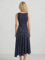 Rear view of a woman wearing a navy blue sleeveless midi dress with white polka dots.