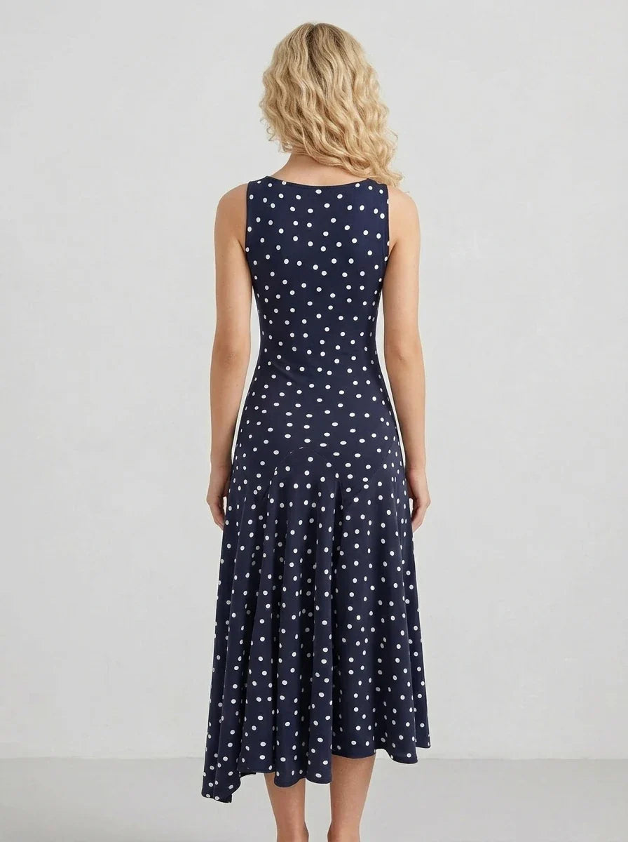 Rear view of a woman wearing a navy blue sleeveless midi dress with white polka dots.