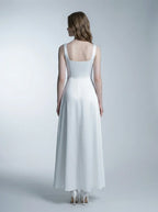 Woman wearing a white satin sleeveless A-line wedding dress with a square neckline, back view