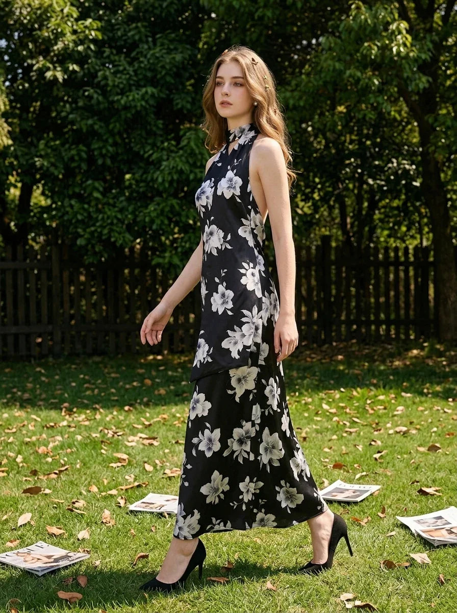 woman wearing a black floral maxi dress with a halter neck walking on grass