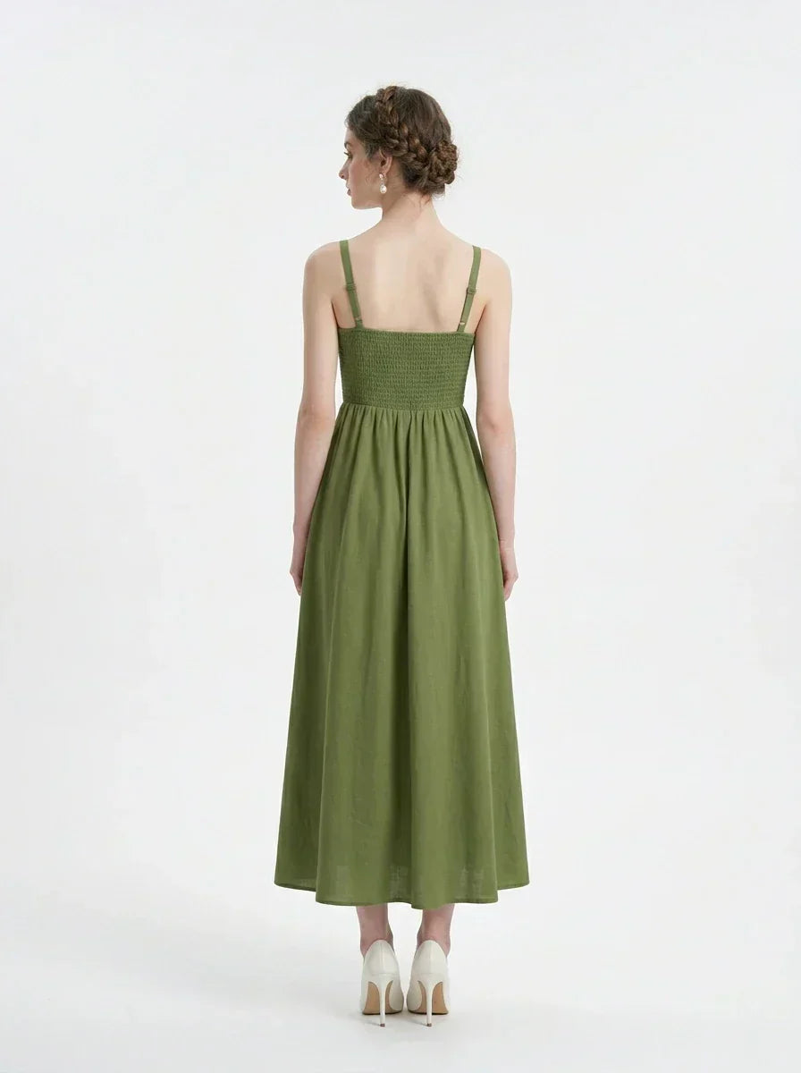 Back view of a woman in a green linen midi dress with a smocked bodice and square neckline.