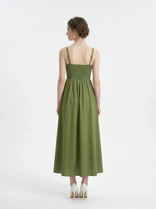 Back view of a woman in a green linen midi dress with a smocked bodice and square neckline.