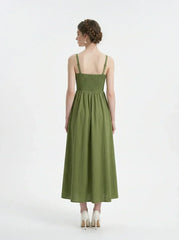 Back view of a woman in a green linen midi dress with a smocked bodice and square neckline.