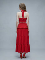Woman wearing a red halter crop top and a tiered maxi skirt, back view